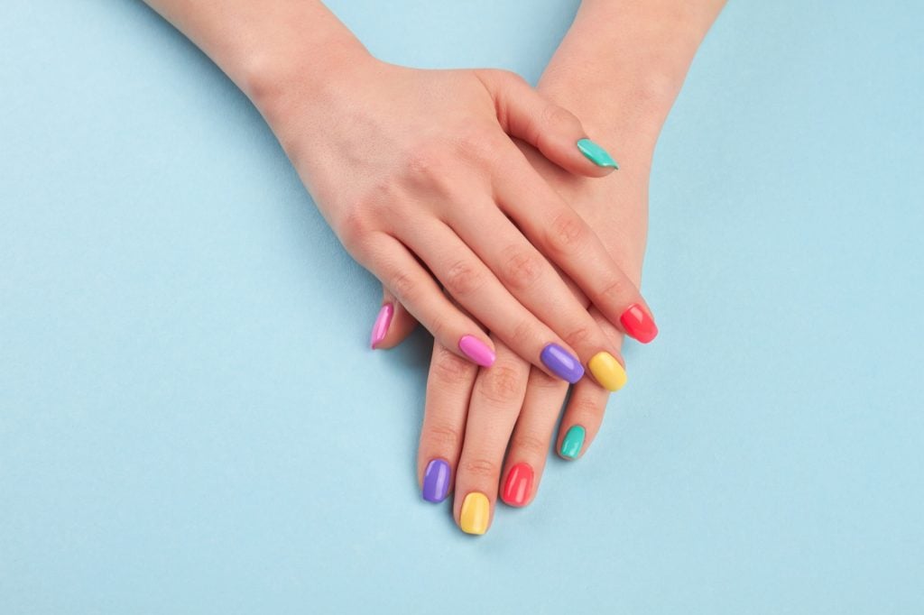 Manicured hands with stylish colorful nails on a light blue background