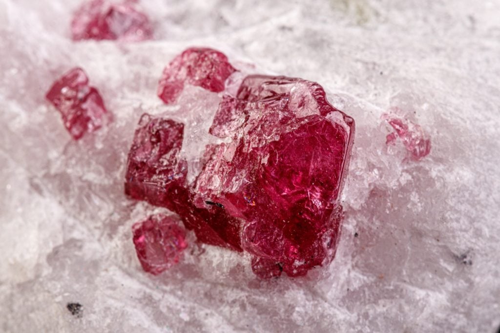 Mineral macro shot of small spinel crystals on white calcite