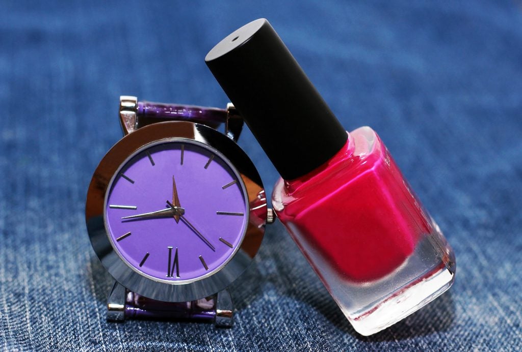 Montre-bracelet violette moderne à côté du vernis à ongles