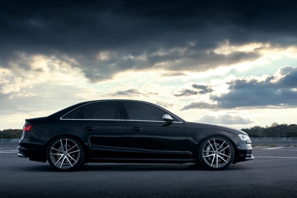 Parked black car below cloudy sky
