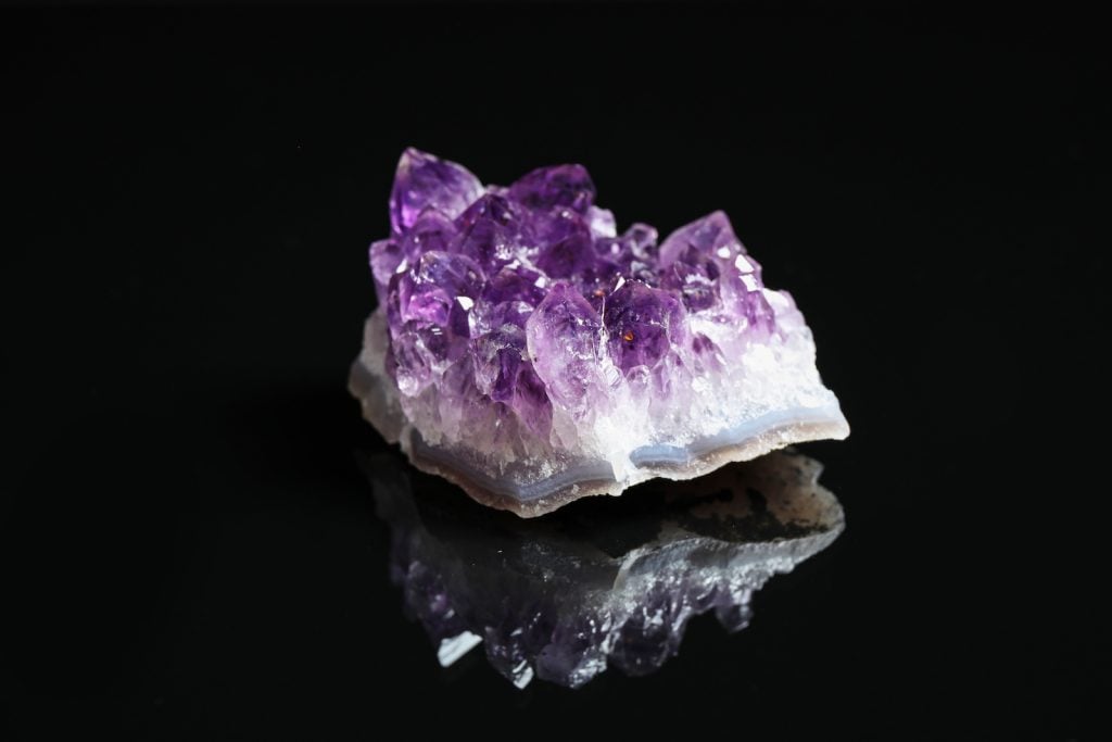 Piece of raw cut purple amethyst gemstone on black background