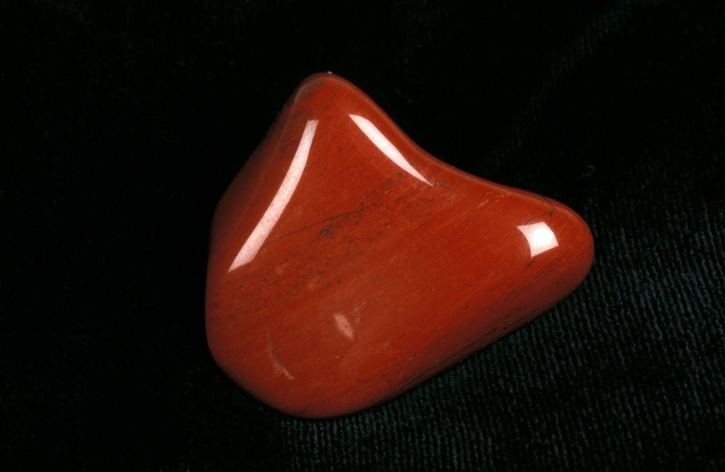 Polished red jasper stone on a dark background