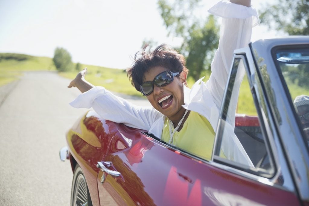 Retrato de animado mulher de meia idade no carro conversível vermelho