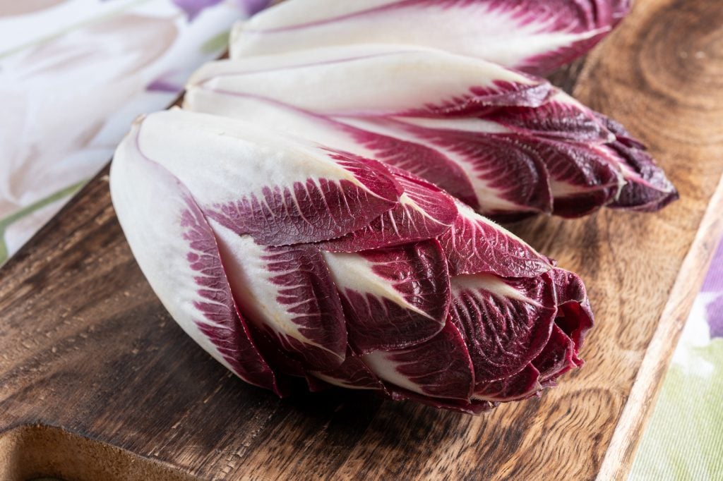 Close up of purple Belgian endive on a wooden chopping board