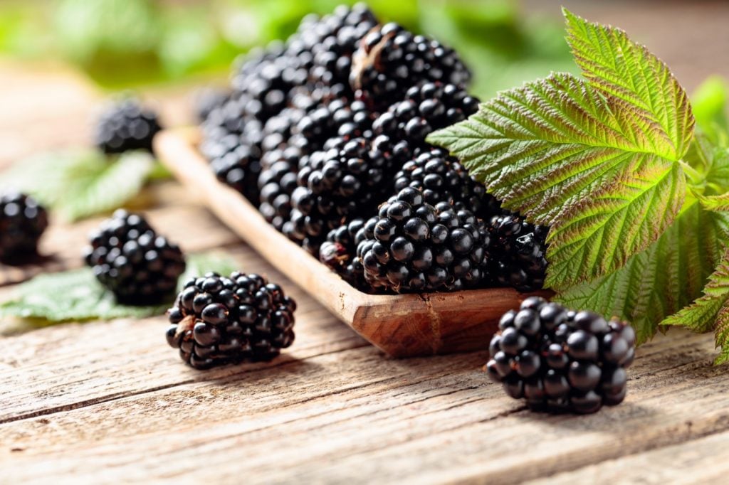 Ripe blackberries with leaves on a wooden table