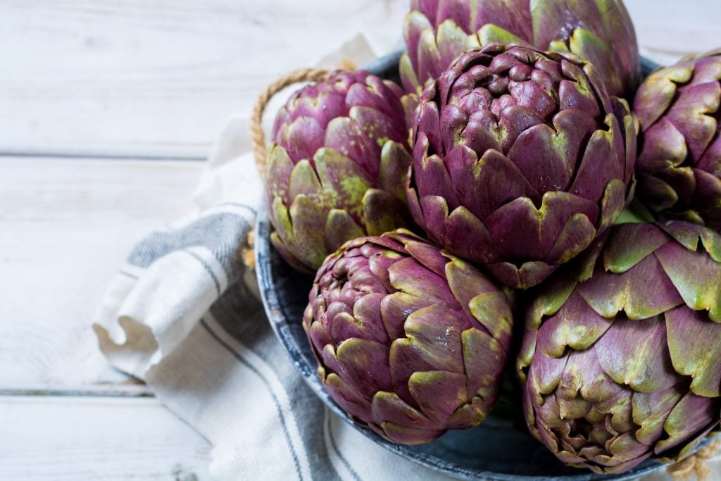 Fresh romanesco artichokes purple flower heads in a bowle