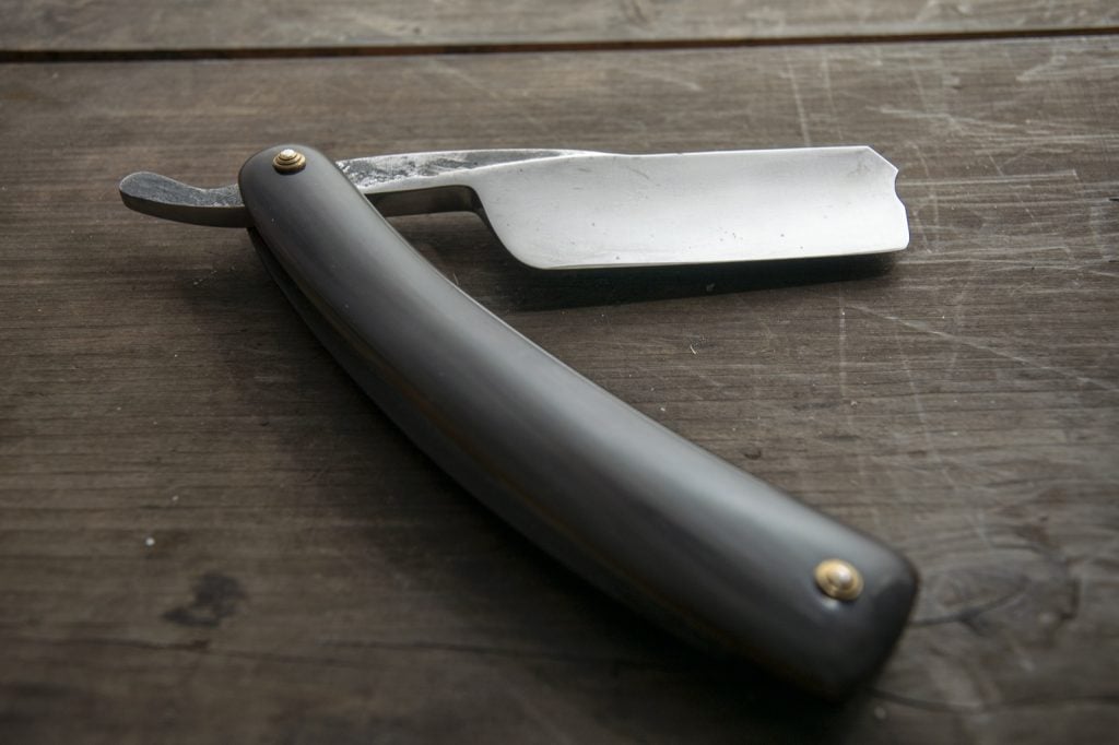 Sharp straight barber razor on rustic wooden table