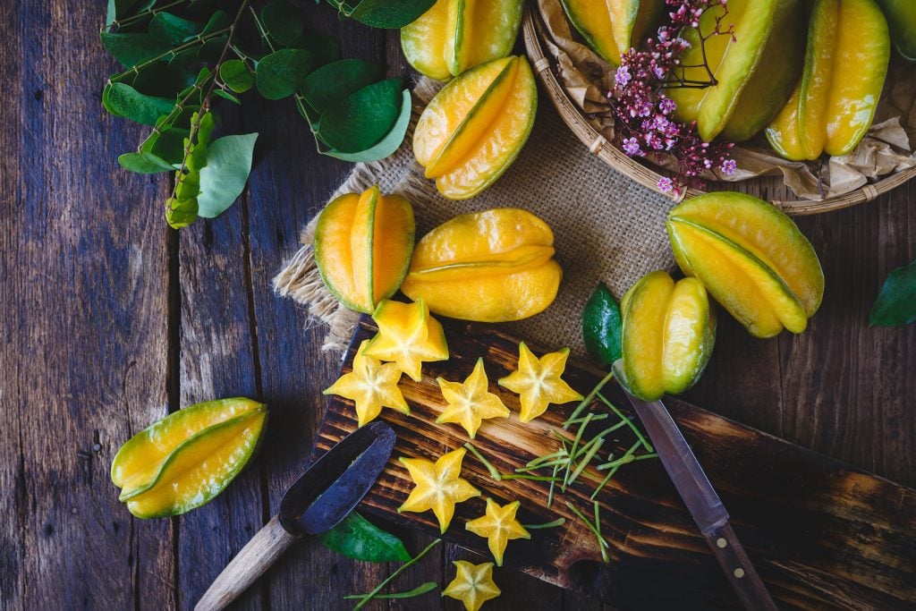 Bunch of starfruits on an old rustic wooden table some are whole and some are cut out into stars