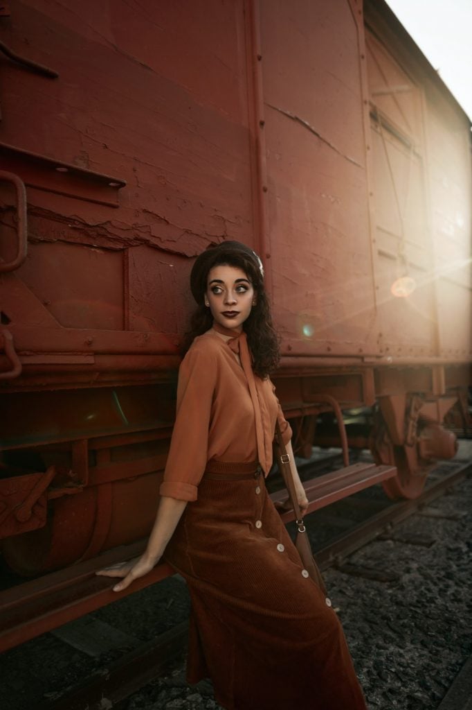 Woman wearing an outfit in analogous colors posing in front of train wagon