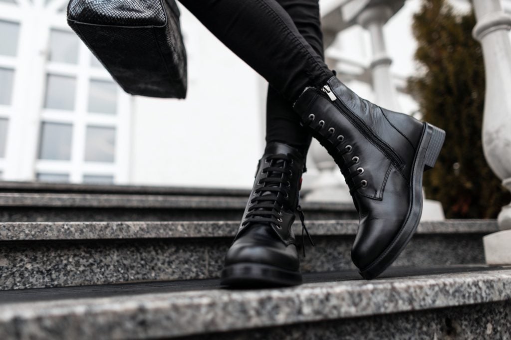 Woman in black leather shoes with a handbag standing on stone steps