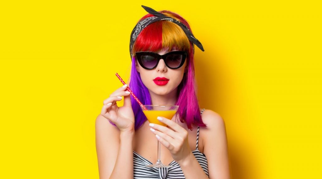 Woman with multicolored hair holding lemonade on yellow background