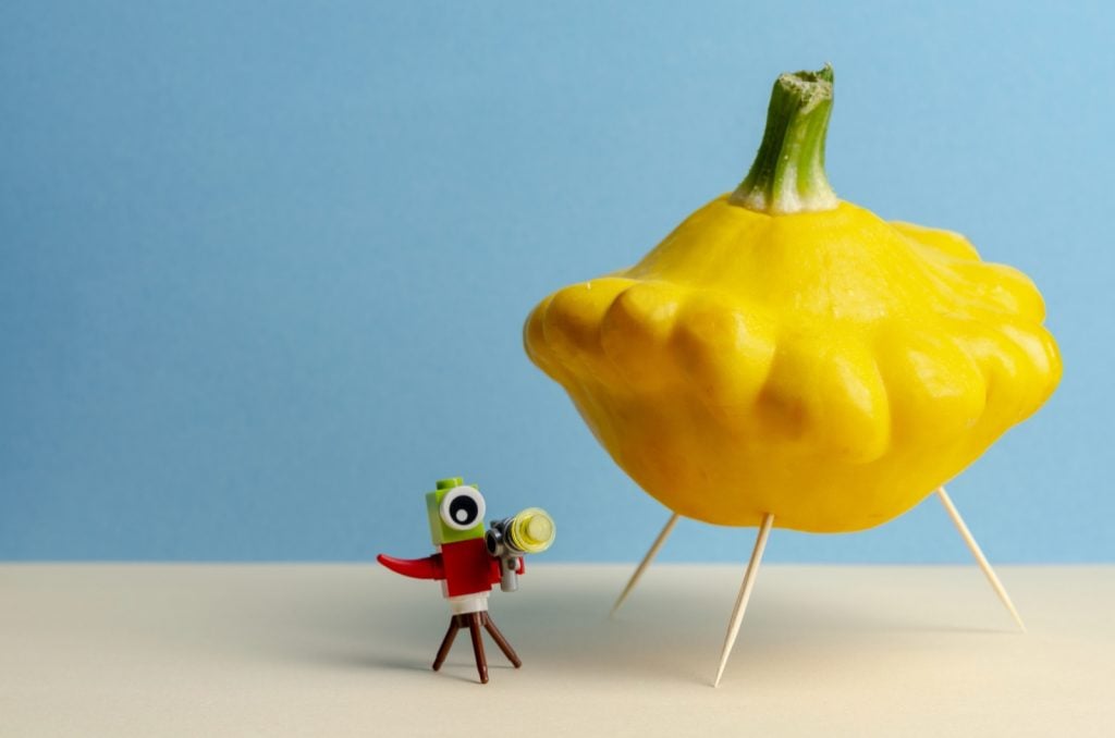 Yellow pattypan squash that looks like a ufo on a colored background